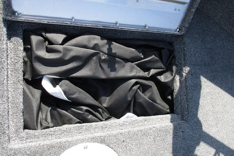 Slide: The Image of Storage compartment in 2027 Tracker Super Guide V-16 SC boat, containing black fabric. - 15