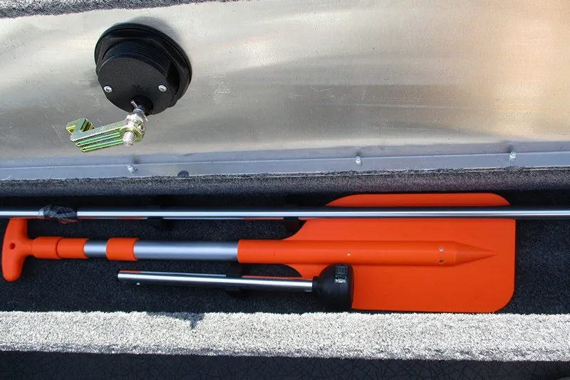 Slide: The Image of Storage compartment in a 2027 Tracker Super Guide V-16 SC boat with orange paddle and accessories. - 18