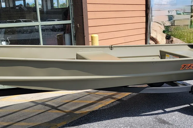 The Image of 2027 Tracker Grizzly 14 Jon boat displayed outdoors on a trailer. - 0