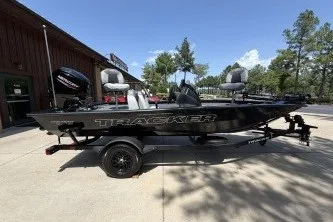 The Image of 2027 Tracker Pro Team 175 boat on trailer, parked outdoors under clear blue sky. - 0