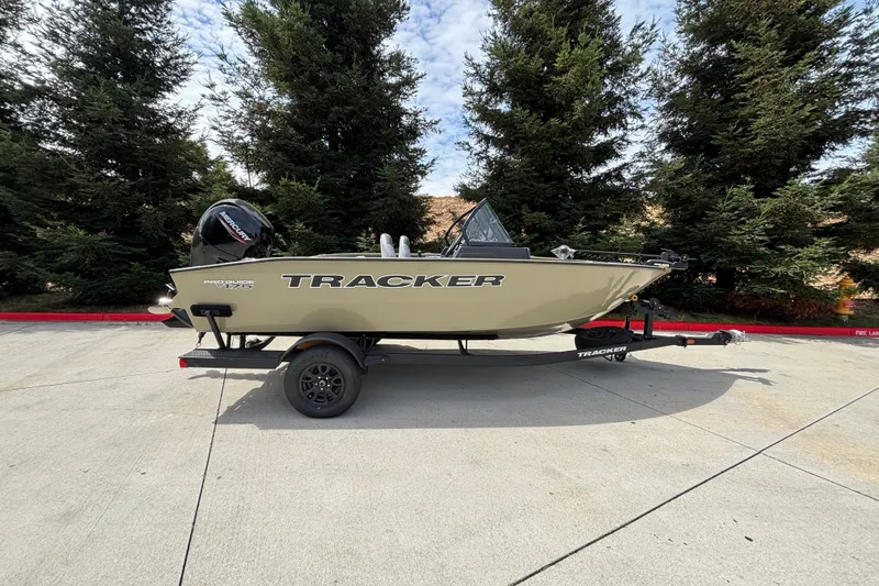 The Image of A 2027 Tracker Pro Guide V-175 Combo on a trailer, set against tall trees. - 0