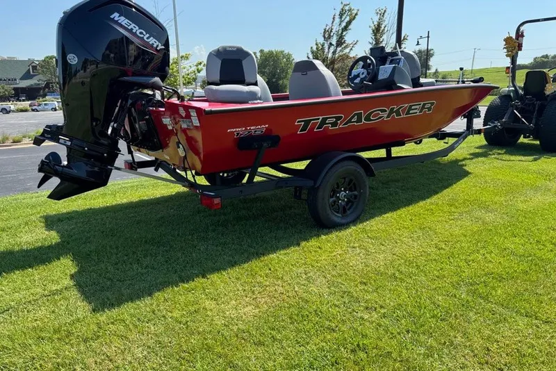 The Image of 2027 Tracker Pro Team 175 boat on trailer, red exterior, parked on grass. - 0
