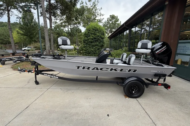 The Image of 2027 Tracker Pro 170 fishing boat on trailer, parked outdoors near trees and building. - 0