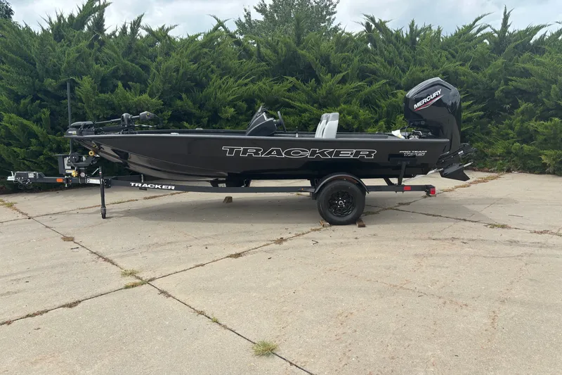 The Image of 2027 Tracker Pro Team 175 boat on trailer, parked outdoors with greenery background. - 0