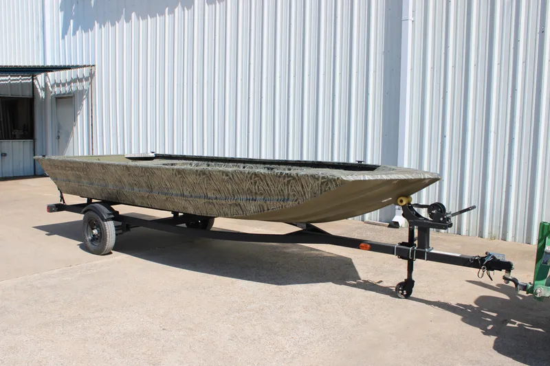 The Image of 2027 Tracker Grizzly 1648 Utility boat on trailer, parked outside a metal building. - 0