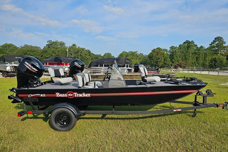 The Image of 2027 Tracker Bass Tracker Classic XL boat on trailer, parked on grass under blue sky. - 1