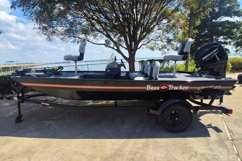 The Image of 2027 Tracker Bass Tracker Classic XL boat on trailer, parked near a scenic waterfront. - 0