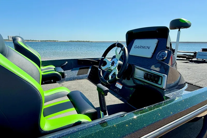 Slide: The Image of 2027 Nitro Z18 XL Pro boat interior with green seats and Garmin dashboard by the water. - 9