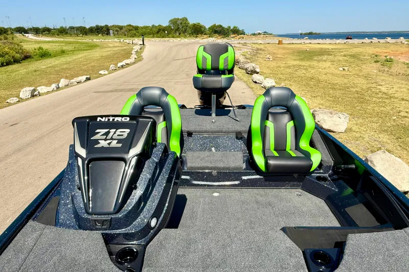 Slide: The Image of 2027 Nitro Z18 XL Pro boat with green and black seats on a lakeside road. - 18