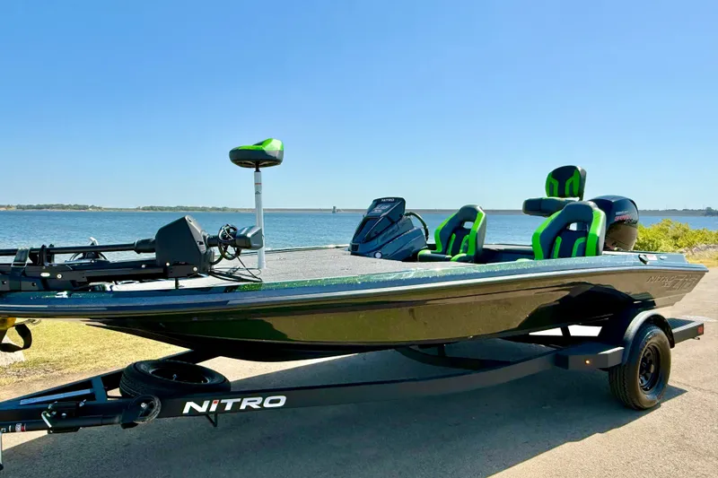 The Image of 2027 Nitro Z18 XL Pro boat by the water, featuring green-accented seats. - 0