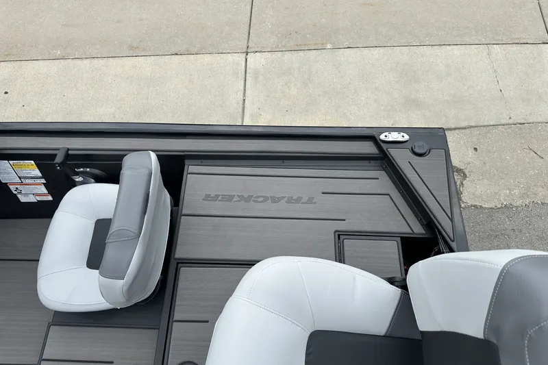 Slide: The Image of 2027 Tracker Pro 170 boat interior with gray seating and deck, parked on pavement. - 21