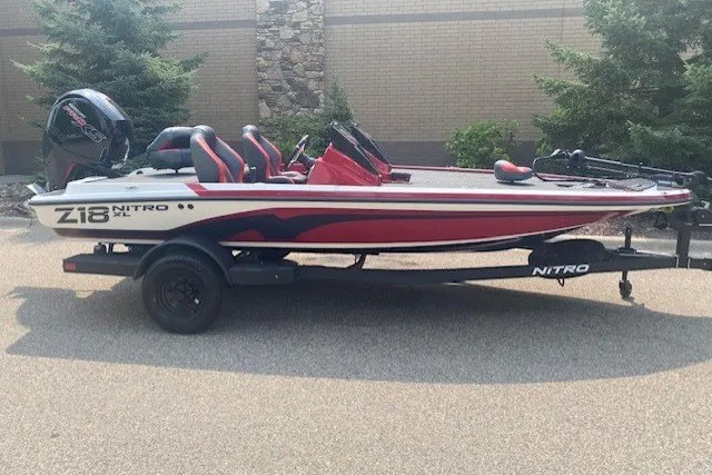 The Image of 2027 Nitro Z18 XL boat on trailer, red and white design, parked outdoors. - 0