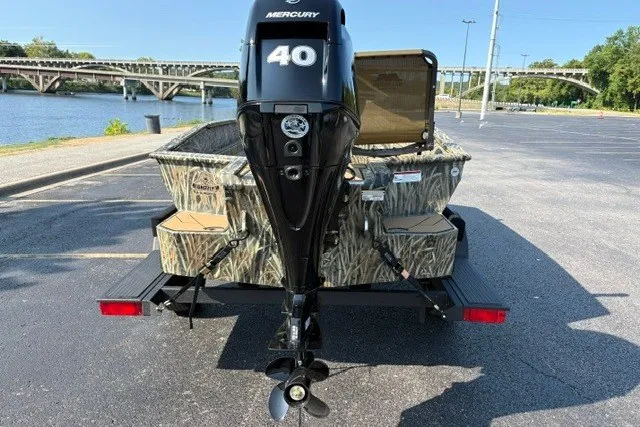 Slide: The Image of 2027 Tracker Grizzly 1553 Timber boat with Mercury 40 engine, parked near a river. - 14