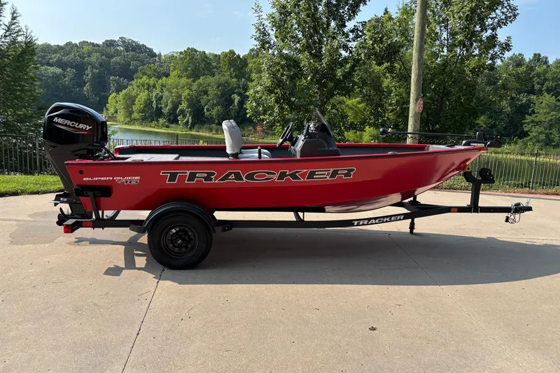 The Image of Red 2027 Tracker Super Guide V-16 SC boat on trailer, parked near a scenic lake. - 0