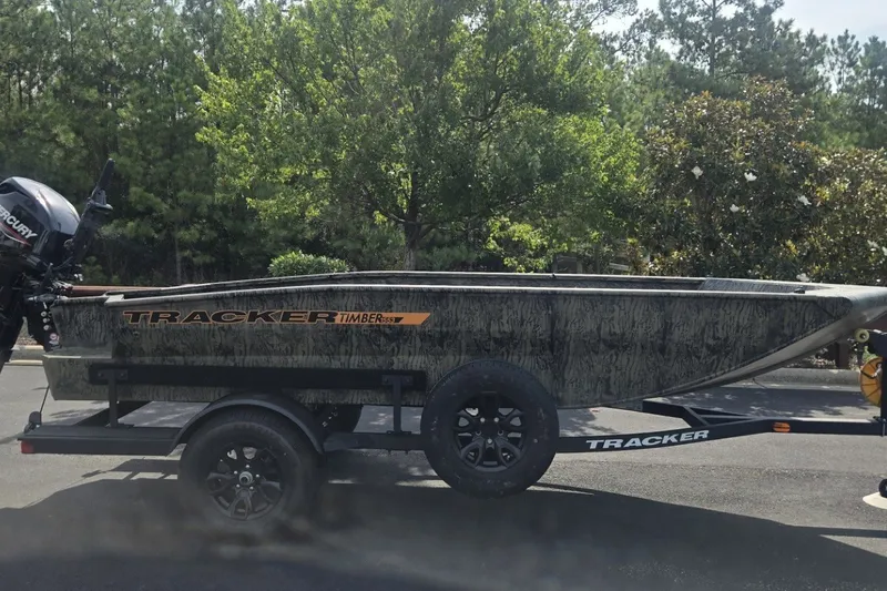 The Image of 2027 Tracker Grizzly 1553 Timber boat on trailer, parked outdoors with trees in background. - 0