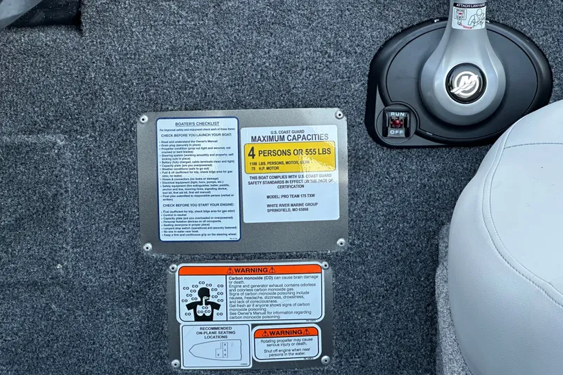 Slide: The Image of 2027 Tracker Pro Team 175 boat capacity and safety labels on carpeted surface. - 15