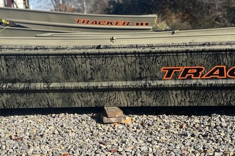 The Image of 2027 Tracker Grizzly 15 Jon boat with camouflage design on gravel surface. - 0
