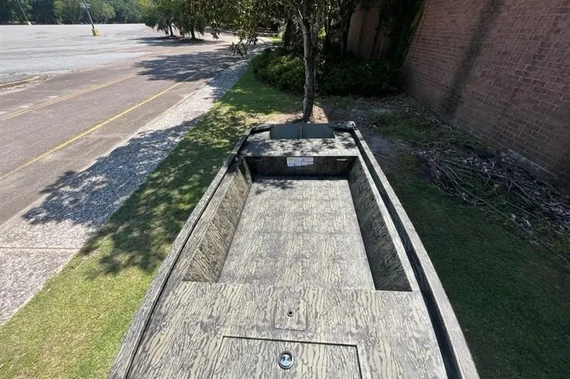 Slide: The Image of 2027 Tracker Grizzly 1648 Utility boat parked on grass near a brick wall. - 13