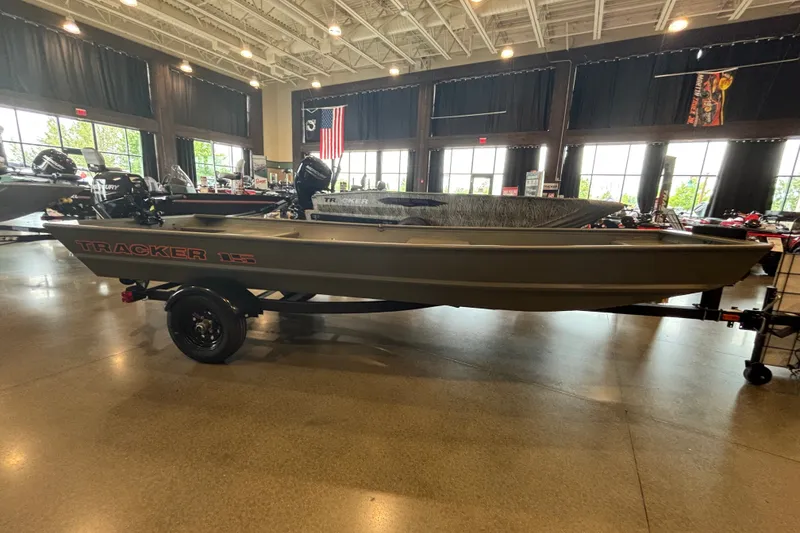 The Image of 2027 Tracker Grizzly 15 Jon boat displayed indoors on a trailer. - 0