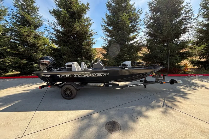 The Image of 2027 Tracker Pro Team 175 boat on trailer, parked outdoors near trees. - 0
