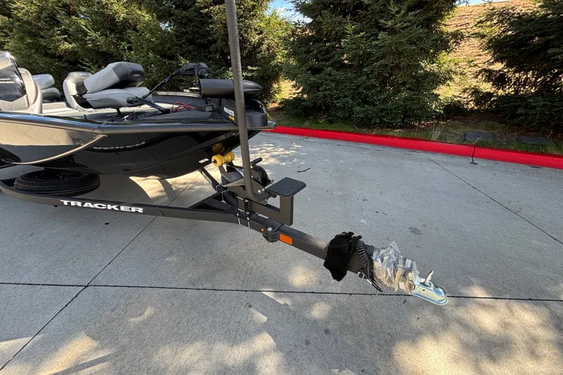Slide: The Image of 2027 Tracker Pro Team 175 boat on trailer, parked on concrete, surrounded by trees. - 19