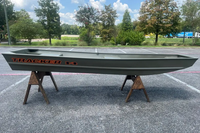 The Image of 2027 Tracker Grizzly 14 Jon boat displayed outdoors on wooden stands. - 0
