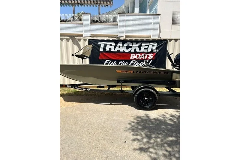 The Image of 2027 Tracker Grizzly 1553 Timber boat displayed outdoors with promotional banner. - 0