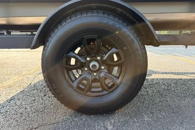 Slide: The Image of Black wheel of 2027 Tracker Grizzly 1553 Timber on asphalt surface. - 19