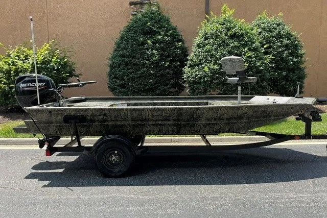 The Image of 2027 Tracker Grizzly 1654 T Sportsman boat on trailer, parked outdoors. - 0