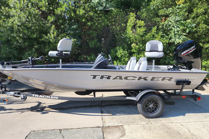 The Image of 2027 Tracker Pro Team 175 boat on trailer, parked outdoors with lush greenery background. - 0