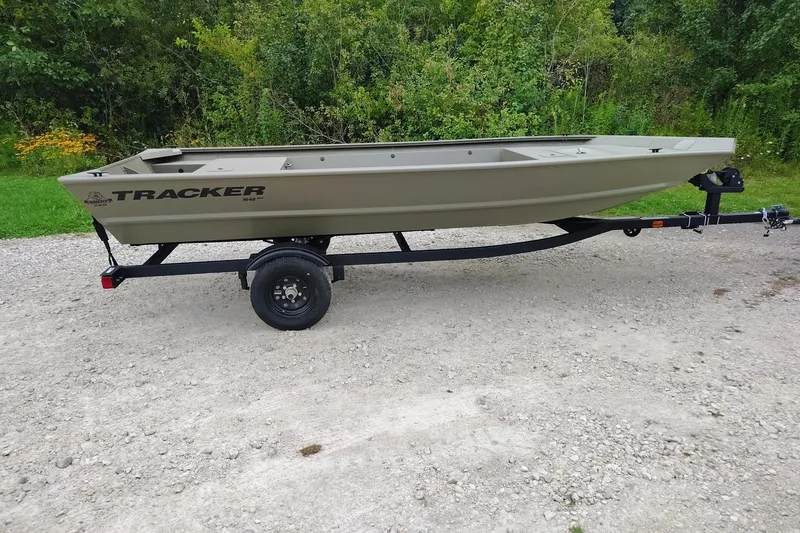 The Image of 2027 Tracker Grizzly 1648 Utility boat on trailer, parked on gravel path. - 0