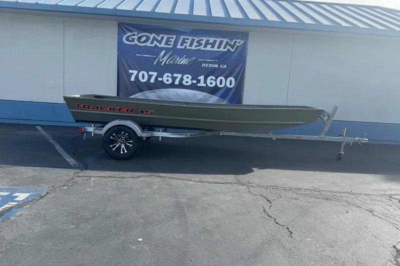 Slide: The Image of 2027 Tracker Grizzly 15 Jon boat on trailer outside marine shop. - 17