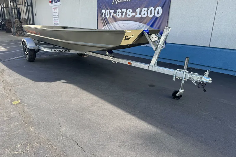 Slide: The Image of 2027 Tracker Grizzly 15 Jon boat on Karavan trailer, parked outdoors. - 27