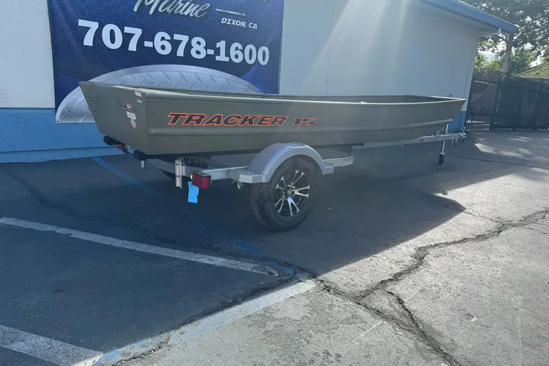 Slide: The Image of 2027 Tracker Grizzly 15 Jon boat on trailer, parked outside a marine shop. - 18