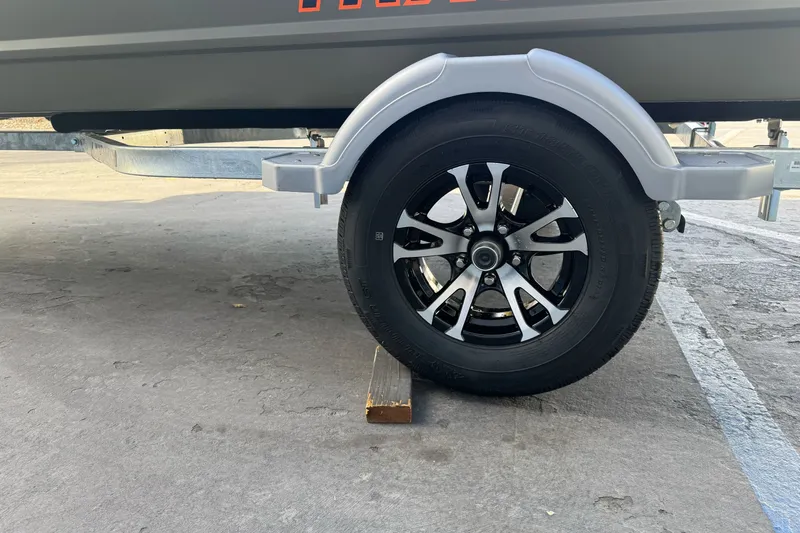Slide: The Image of Trailer wheel of 2027 Tracker Grizzly 15 Jon on a wooden block. - 22