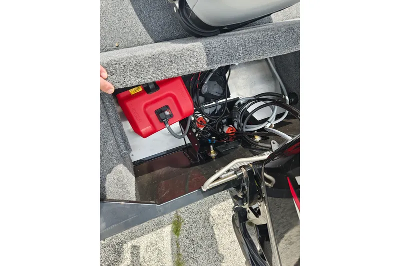 Slide: The Image of 2027 Tracker Bass Tracker Classic XL boat storage compartment with red fuel tank and wiring. - 24