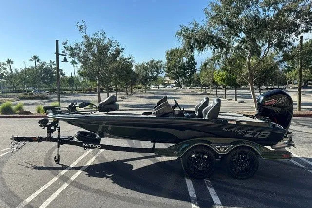 Slide: The Image of 2027 Nitro Z18 XL boat on trailer in parking lot, surrounded by trees. - 1