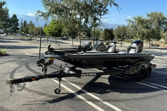 Slide: The Image of 2027 Nitro Z18 XL boat in parking lot, surrounded by trees and mountains. - 2