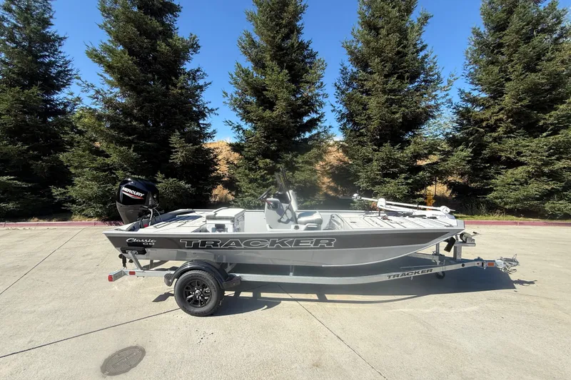 The Image of 2027 Tracker Bass Tracker Classic CC boat on trailer, parked outdoors with trees in background. - 0