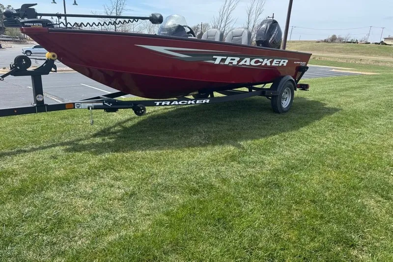 The Image of Red 2027 Tracker Super Guide V-16 SC boat on trailer, parked on grass. - 0