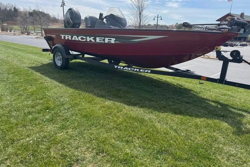 Slide: The Image of Red 2027 Tracker Super Guide V-16 SC boat on trailer, parked on grass. - 14