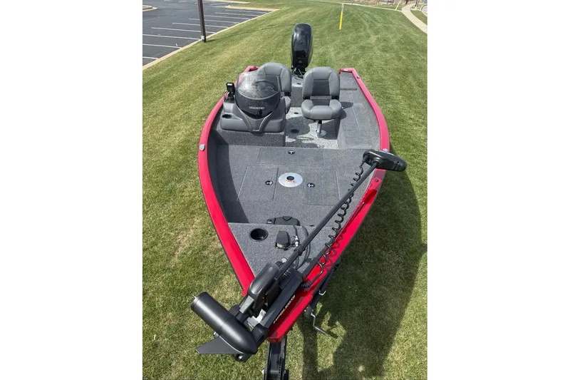 Slide: The Image of Red 2027 Tracker Super Guide V-16 SC fishing boat on grass, featuring dual seats and trolling motor. - 15
