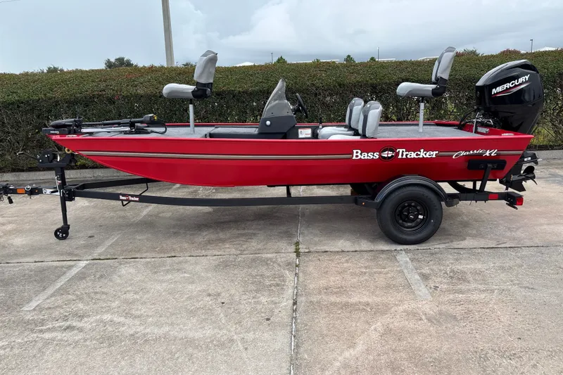 The Image of 2027 Tracker Bass Tracker Classic XL boat, red, on trailer, parked outdoors. - 0