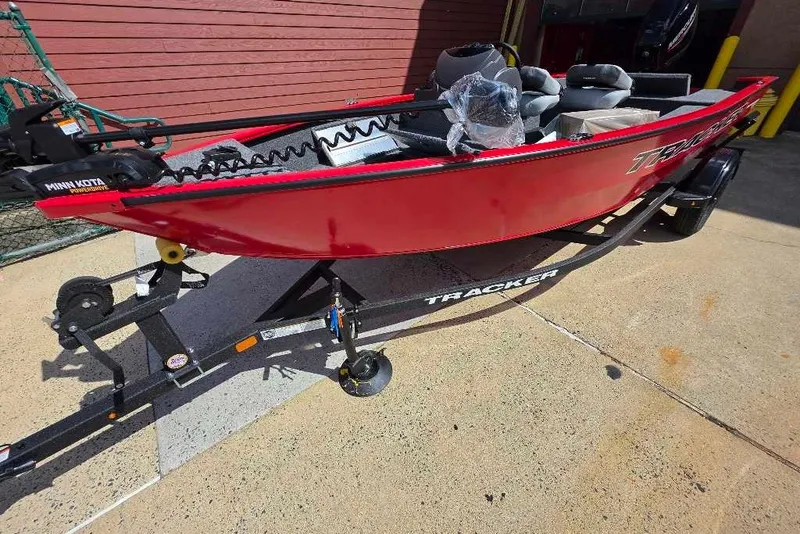 The Image of Red 2027 Tracker Super Guide V-16 SC boat on trailer, parked outdoors. - 0