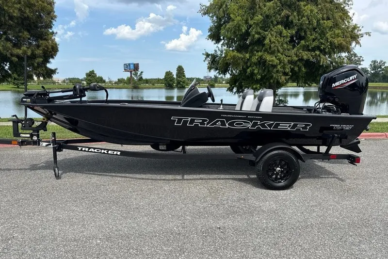 The Image of 2027 Tracker Pro Team 175 boat on trailer by a lake, featuring Mercury engine. - 0