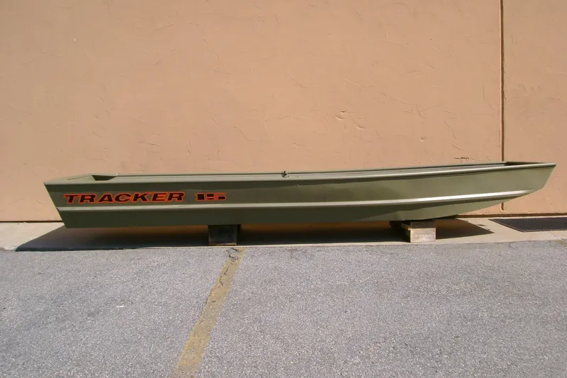 The Image of 2027 Tracker Grizzly 15 Jon boat in olive green, displayed outdoors on blocks. - 0
