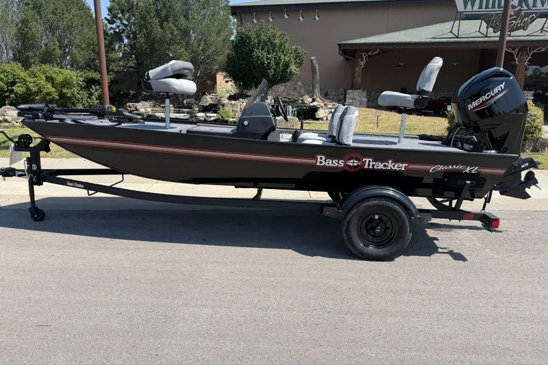 The Image of 2027 Tracker Bass Tracker Classic XL boat on trailer, parked outdoors. - 0