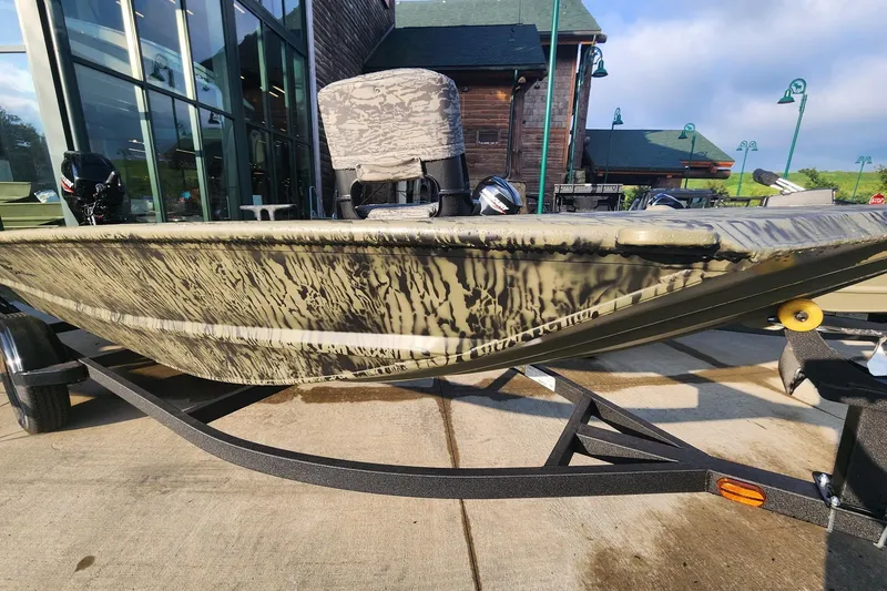 The Image of 2027 Tracker Grizzly 1654 T Sportsman boat on trailer, camo design, outdoor setting. - 0