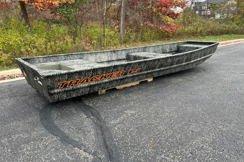 The Image of 2027 Tracker Grizzly 15 Jon boat on pavement, surrounded by autumn foliage. - 0