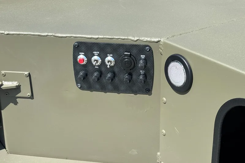 Slide: The Image of Control panel on 2027 Tracker Grizzly 1654 T Sportsman boat, featuring switches and a 12V outlet. - 15